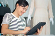 © DG PhotoStock - Happy beautiful Asian young woman working in the fashion design studio.