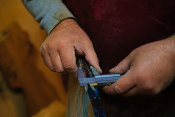 Wall Mural - Close-up on hands measuring wood; precision and focus. Represents the meticulous nature of handcrafted goods.