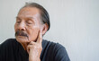 © Kunlathida - Portrait of retirement aged Asian man in profile pointig finger on his ear isolated on white with copy space.