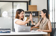 © NanSan - Two Asian colleagues, freelance writer and graphic designer discussing about creating characters in screenplays work and smiling with tablets and a laptop, journalist, artist, giving high five