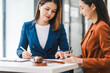 © NanSan - Two young and middle-aged Asian women lawyers in formal suits discuss legal contract, focusing on legislation and women's rights in law office.
