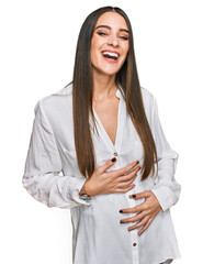 Wall Mural - Young beautiful woman wearing casual white shirt smiling and laughing hard out loud because funny crazy joke with hands on body.