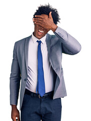 Wall Mural - Handsome african american man with afro hair wearing business jacket smiling and laughing with hand on face covering eyes for surprise. blind concept.