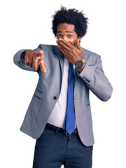 Poster - Handsome african american man with afro hair wearing business jacket laughing at you, pointing finger to the camera with hand over mouth, shame expression