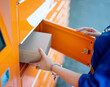 © M-Production - Woman sending or receiving mail via automated self-service pos terminal machine.