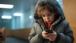 Lonely little elementary school desoriented sad alone child with smartphone in winter clothes in a hospital or office premises waiting for sick parent