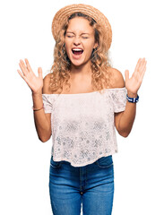 Wall Mural - Beautiful caucasian woman wearing summer hat celebrating mad and crazy for success with arms raised and closed eyes screaming excited. winner concept