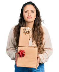 Wall Mural - Young hispanic girl holding gifts depressed and worry for distress, crying angry and afraid. sad expression.