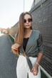 © alones - Beautiful stylish elegant glamorous girl with vintage sunglasses in fashion casual clothes with a shirt stands near a black brick wall on the street
