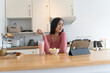 © Charlie's - Asian woman working and eating in home kitchen counter busy work from home