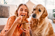 Portrait of a beautiful woman sitting and enjoying with closed eyes a delivery noodle and her dog is sitting next to her, who is pitifully begging for food for people. The dog wants to steal food.