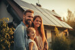 Happy family standing in front of a house with solar panels on roof. Green, renewable and clean energy