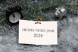 Frohes Neues Jahr 2024: Glücksschwein, Wecker  und einer Karte mit Glückwünschen für das neue Jahr.