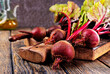 fresh beets on cutting board, set on wooden table viewed from above