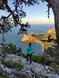 Photo of a girl stands on top of the mountain on the background of a sea bay at sunset in Crimea
