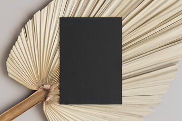 Sticker - Black invitation card mockup with a dried palm leaf on the beige table. 5x7 ratio, similar to A6, A5.