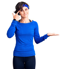 Sticker - Beautiful young woman with short hair wearing training workout clothes confused and annoyed with open palm showing copy space and pointing finger to forehead. think about it.