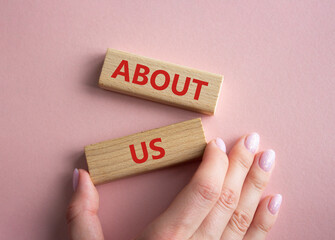 Sticker - About us symbol. Concept word About us on wooden blocks. Businessman hand. Beautiful pink background. Business and About us concept. Copy space