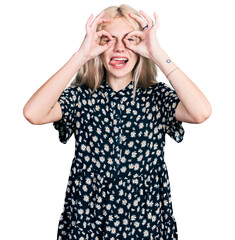 Wall Mural - Young caucasian woman together doing ok gesture like binoculars sticking tongue out, eyes looking through fingers. crazy expression.