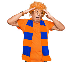 Sticker - Senior hispanic man football hooligan cheering game suffering from headache desperate and stressed because pain and migraine. hands on head.