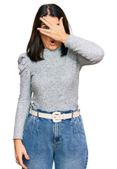 Poster - Middle age brunette woman wearing casual clothes peeking in shock covering face and eyes with hand, looking through fingers with embarrassed expression.