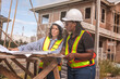 © Supavadee - Real estate concept.female black engineer, contractor standing, with blueprints to inspect house construction work with project manager following work progress and discussing house construction prolem