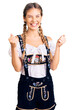 © Krakenimages.com - Beautiful caucasian woman with blonde hair wearing octoberfest traditional clothes excited for success with arms raised and eyes closed celebrating victory smiling. winner concept.