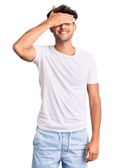 Poster - Young hispanic man wearing casual clothes smiling and laughing with hand on face covering eyes for surprise. blind concept.