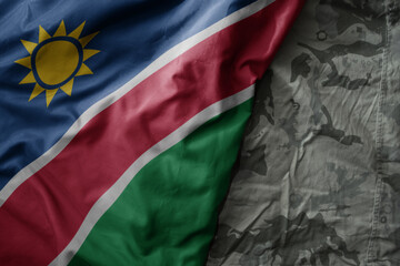 Wall Mural - waving flag of namibia on the old khaki texture background. military concept.