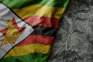 Wall Mural - waving flag of zimbabwe on the old khaki texture background. military concept.