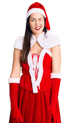 Sticker - Young beautiful caucasian woman wearing santa claus costume winking looking at the camera with sexy expression, cheerful and happy face.