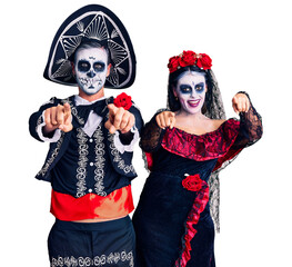 Canvas Print - Young couple wearing mexican day of the dead costume over background pointing to you and the camera with fingers, smiling positive and cheerful