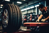 Fototapeta Do przedpokoju - A man is seen working on a tire in a garage. This image can be used to depict automotive maintenance and repair