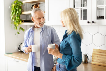 Wall Mural - Happy elderly couple drinking morning coffee in kitchen