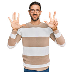 Canvas Print - Handsome man with beard wearing casual clothes and glasses showing and pointing up with fingers number eight while smiling confident and happy.