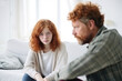 © Fotoksa - Close up man in front and sad girl with freckles behind sit at sofa avoid to talk after quarrel at home, offended red-haired teen daughter and middle aged father argument, adolescence problems
