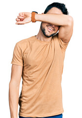 Canvas Print - Hispanic man with beard wearing casual t shirt covering eyes with arm smiling cheerful and funny. blind concept.