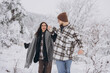 © anatoliycherkas - A young happy and loving couple walking in a snowy forest in the mountains