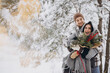 © anatoliycherkas - Cute young couple in love with pine bouquet spending time on Valentine's day in snowy winter forest in mountains