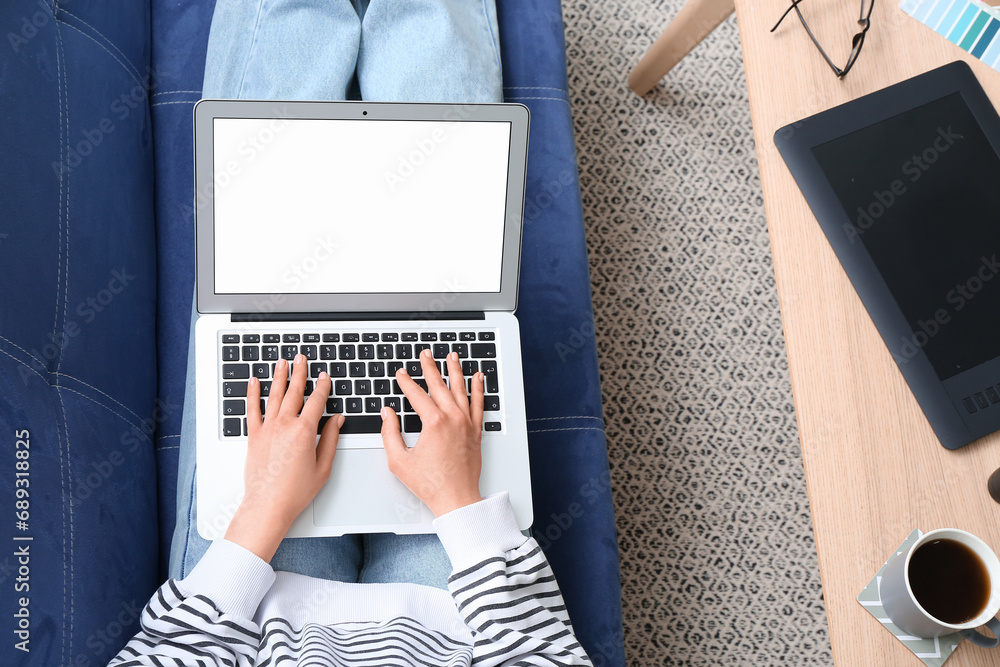 Female designer with laptop lying on sofa