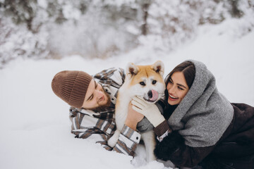 Wall Mural - Happy young couple with akita dog in forest on winter day