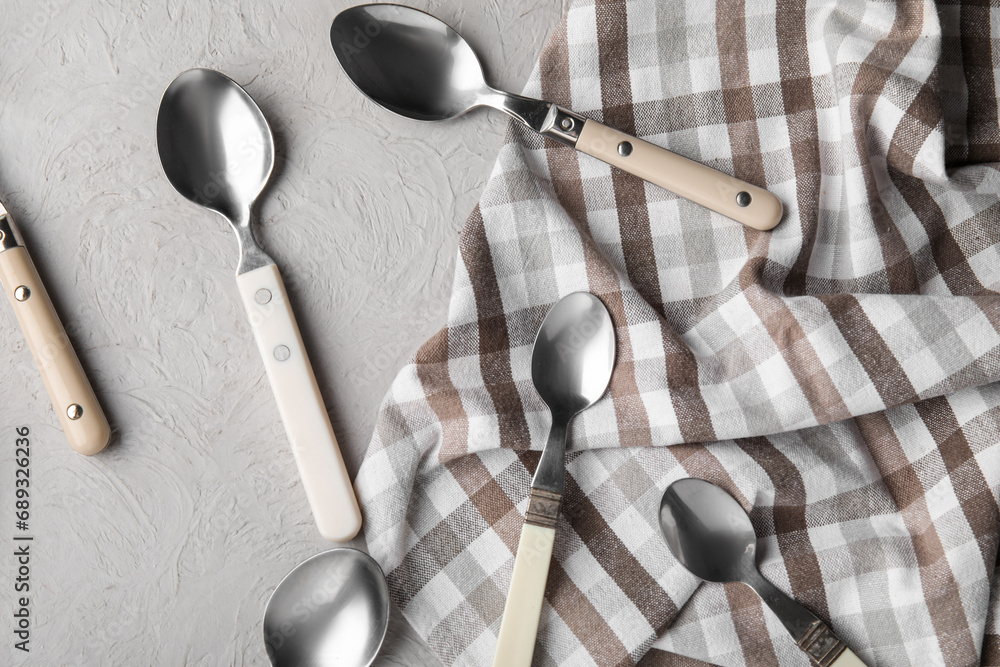 Different silver spoons and napkin on grey background