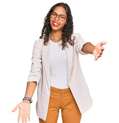 Poster - Young african american girl wearing business clothes smiling cheerful offering hands giving assistance and acceptance.