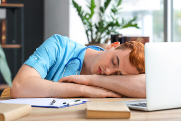 Tired male medical student sleeping at table in library