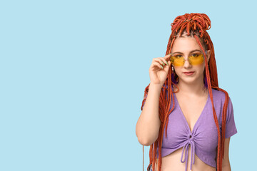 Wall Mural - Portrait of fashionable young woman with dreadlocks on blue background