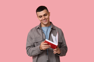 Poster - Handsome young man reading book on pink background