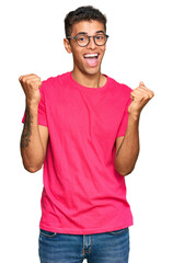 Poster - Young handsome african american man wearing casual clothes screaming proud, celebrating victory and success very excited with raised arms