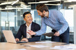 © Liubomir - Two male colleagues work in the office, consult on issues, solve work issues, do paperwork.