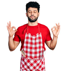 Sticker - Young arab man with beard wearing cook apron relax and smiling with eyes closed doing meditation gesture with fingers. yoga concept.