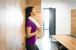 © Dorde - Tired athletic woman standing in locker room and taking a break from exercising. Woman holding gym towel while leaning against the locker in gym.